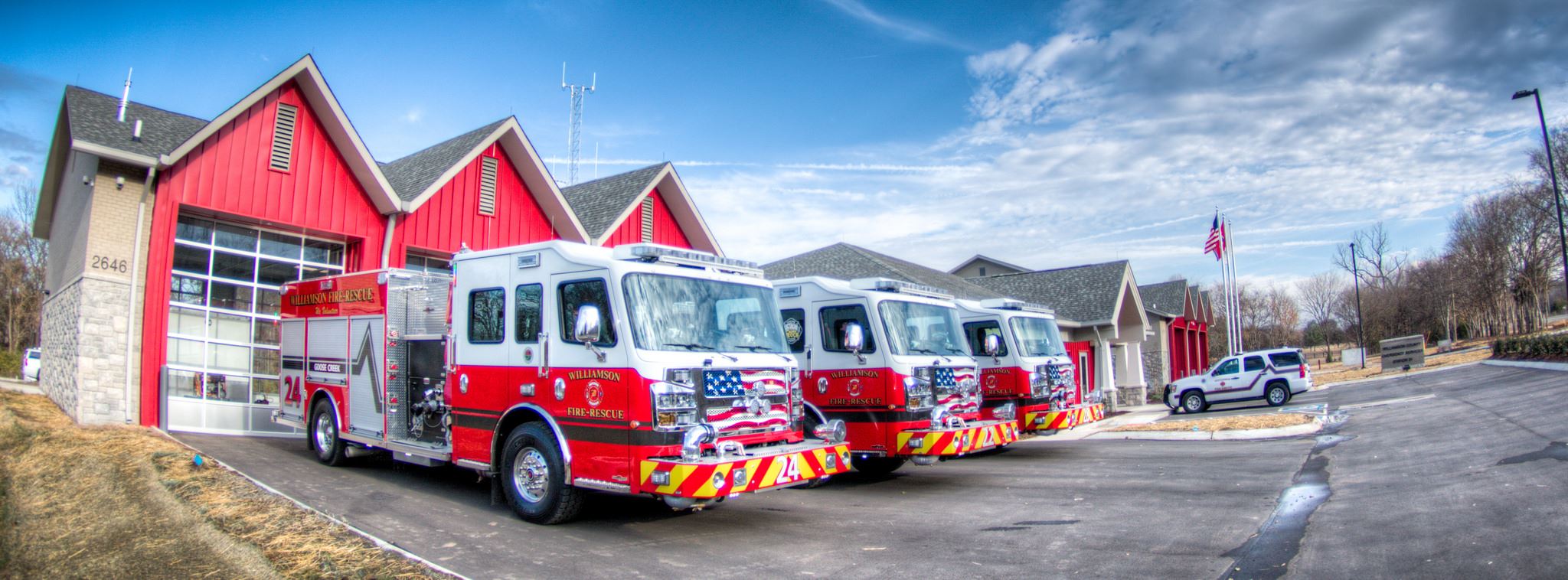 Fire trucks lined up in front of a fire station.