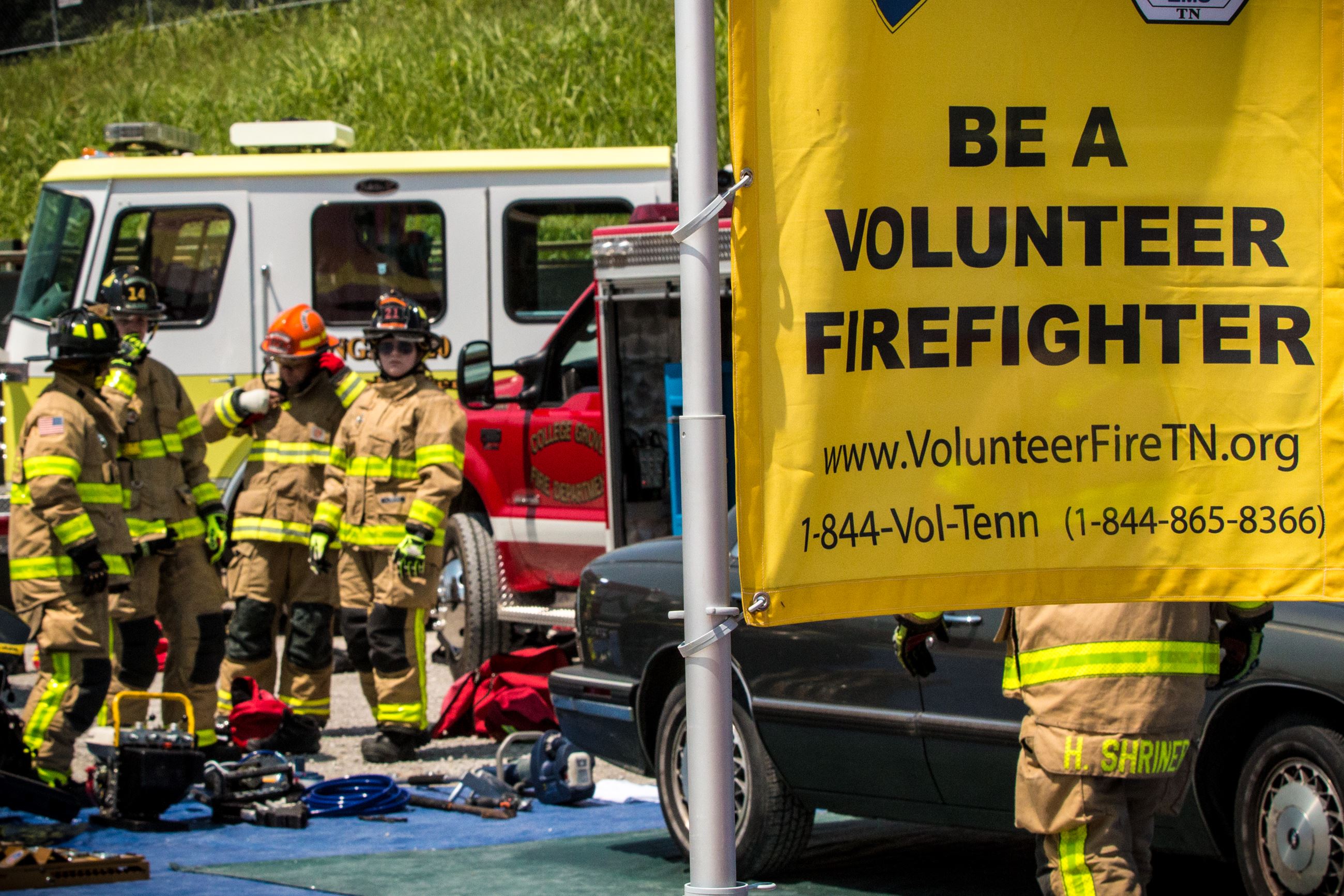 A volunteer firefighter sign and firefighters working an extrication demo at the fair.